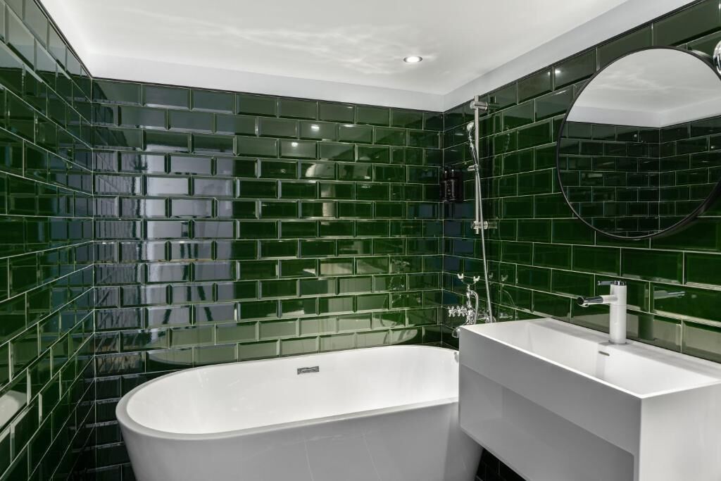 Ein modernes Badezimmer mit freistehender Badewanne, einem weißen Waschtisch und einem großen Spiegel.