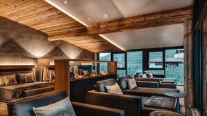 A modern interior with a wooden ceiling, a fireplace, and a view of the countryside. - Dolce Vita Hotel Jagdhof (Laces)