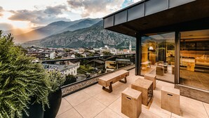 A modern outdoor terrace with a view of a town and mountains. - Dolce Vita Hotel Jagdhof (Laces)