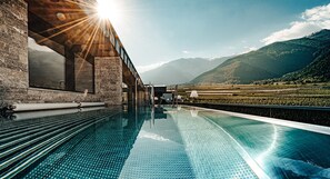 Ein Schwimmbad mit freiem Blick auf die umliegende Landschaft, darunter Berge und ein Weinberg.