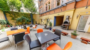 An outdoor seating area with tables and chairs, a brick oven, and potted plants. - Do Step Inn (Vienna)