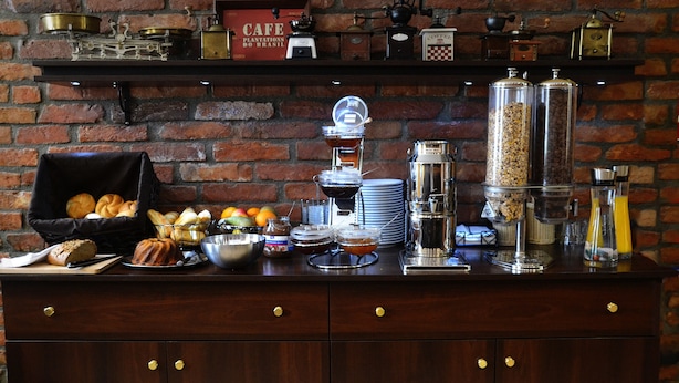 A breakfast buffet with various food items and beverages, including bread, pastries, fruits, and coffee machines. - Do Step Inn (Vienna)