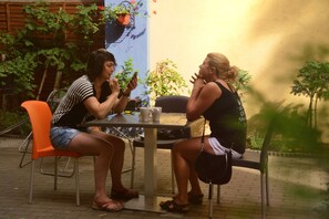 Two people seated at an outdoor table with a potted plant and a cup. - Do Step Inn (Vienna)