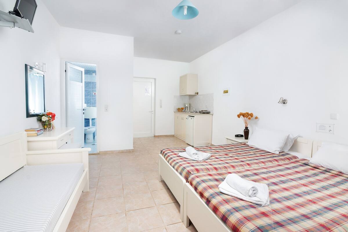 Una habitación de hotel moderna con dos camas, un baño y una kitchenette.