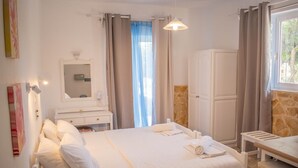 A hotel room with a large bed, a bedside table, a wardrobe, a mirror, and a window with curtains.