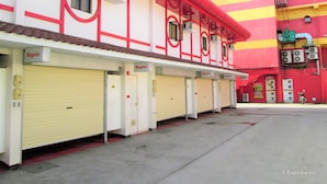 Une rangée de chambres d’hôtel fermées, avec une façade à rayures rouges et jaunes, une galerie couverte et une enseigne indiquant le nom de l’hôtel.