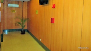 Un hall d’hôtel avec des lambris en bois, un téléviseur fixé au mur et une plante en pot.
