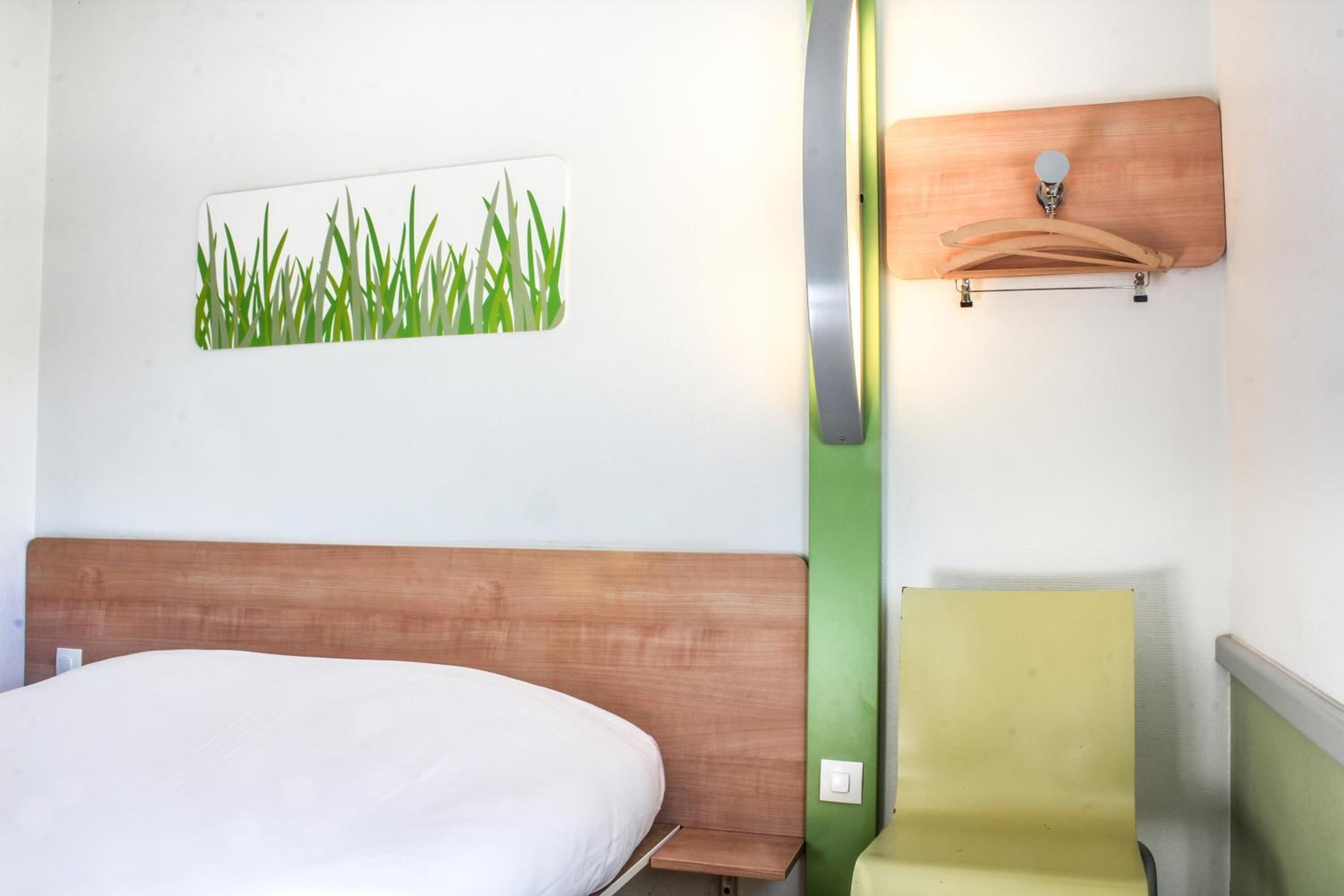 Ein Hotelzimmer mit einem Bett, einem an der Wand befestigten Holzregal und einer grünen Akzentwand.