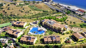 Vista aérea de un resort con varias construcciones, piscina y playa.