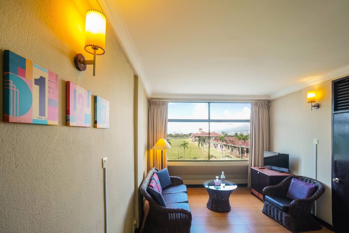 A hotel room with a balcony, a sofa, a television, and a table.