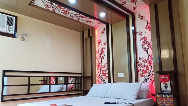 Une chambre d’hôtel avec un lit, une table de chevet avec un téléphone et des motifs floraux sur les murs.