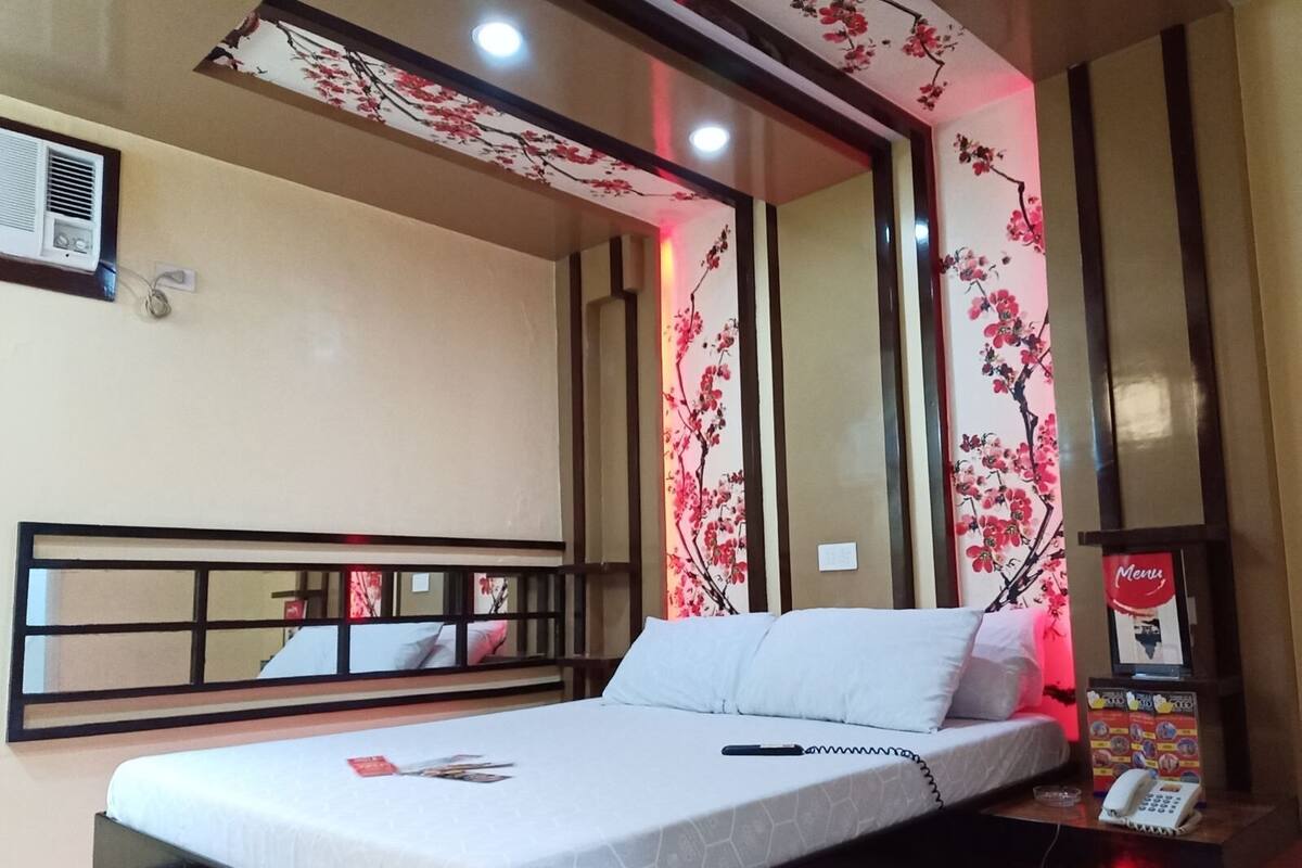 Ein Hotelzimmer mit einem Bett, einem Nachttisch mit Telefon und Wanddekorationen mit floralem Muster.