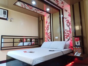 A hotel room with a bed, a bedside table with a phone, and floral wall decorations.