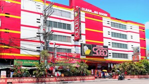 Un hôtel à la façade rouge et blanche, doté de nombreuses fenêtres et d’une grande enseigne bien visible indiquant : « PROPRE… TELLEMENT PROPRE ! ».