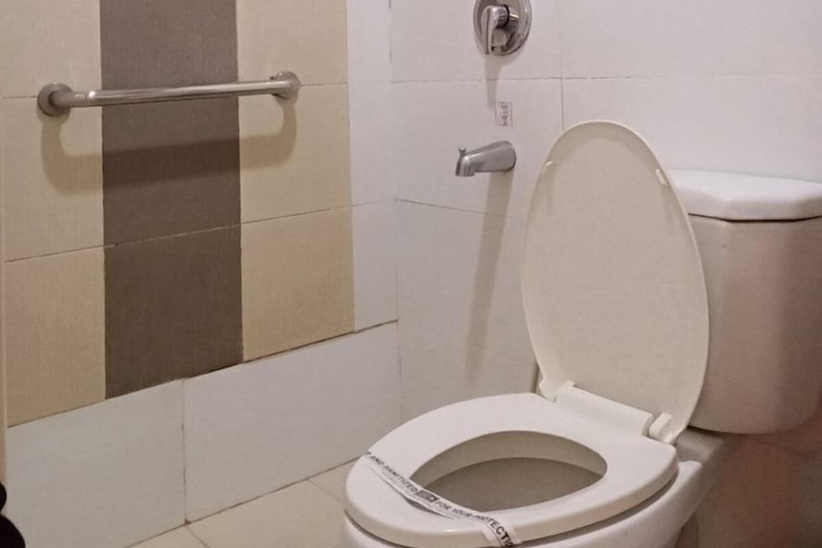 Une salle de bain équipée de toilettes, d’une douche et d’une barre d’appui.