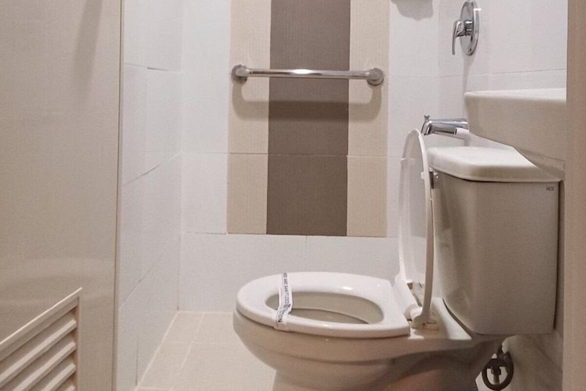 Une salle de bain équipée de toilettes, d’une douche et d’une barre d’appui.