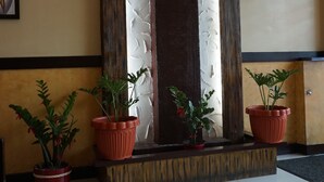 Un espace d’accueil agrémenté d’un mur décoratif, de plantes en pot et d’un sol carrelé.