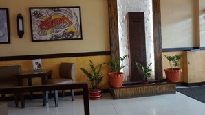 Un hall d’hôtel comprenant un comptoir d’accueil, un espace salon et des plantes en pot.
