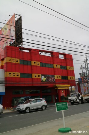 A red building with a sign for a hotel and a parking notice.