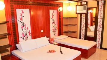 A hotel room with two beds, wooden paneling, a mirror, and a wall-mounted air conditioner.