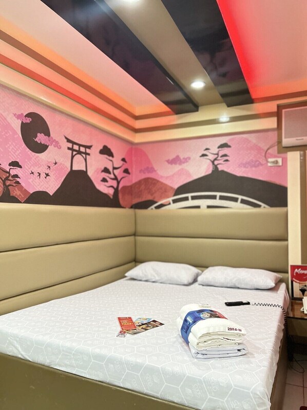 A hotel room with a bed, pillows, a magazine, and a folded towel. - Hotel Sogo Sta. Rosa Laguna (Santa Rosa)