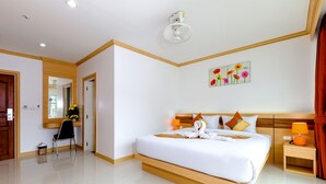Una habitación de hotel moderna con una cama grande, un cabecero de madera, una mesita de noche con una lámpara y un espejo en la pared.
