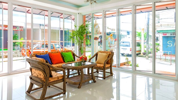 Una habitación luminosa y amplia con ventanas grandes, muebles de mimbre y una mesa central con una planta.