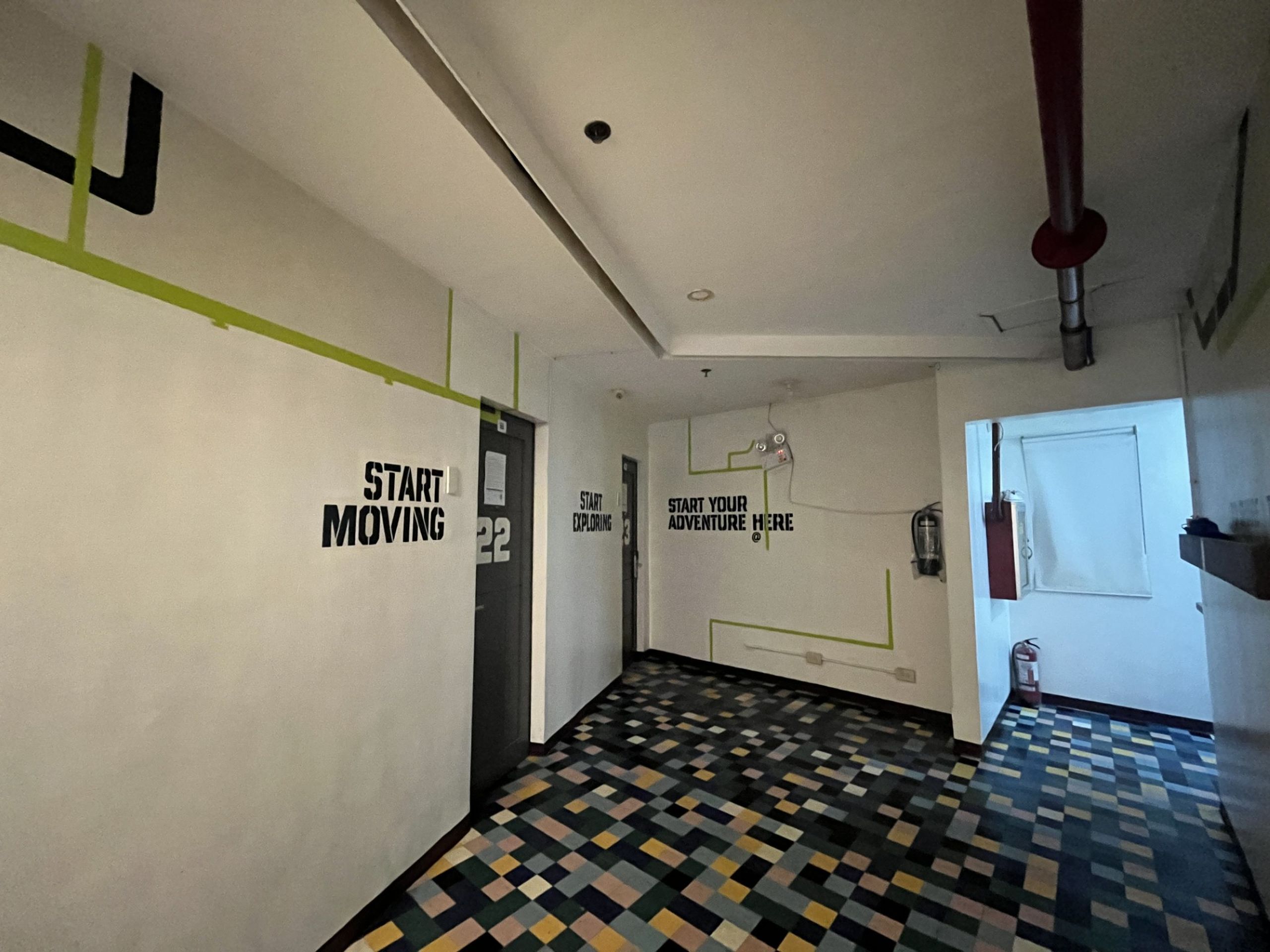 A hallway with motivational wall art, a patterned floor, and a door with a fire extinguisher.