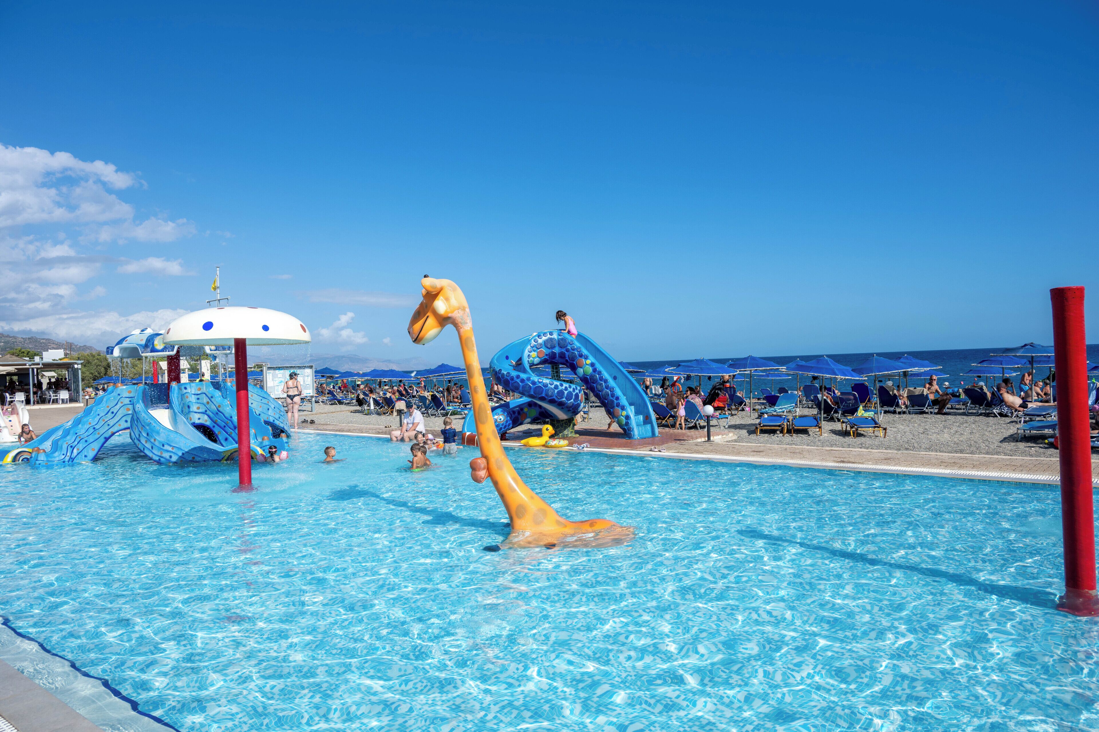 A swimming pool with slides and a giraffe-shaped water feature.