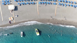 On the beach, black sand, sun loungers, beach umbrellas