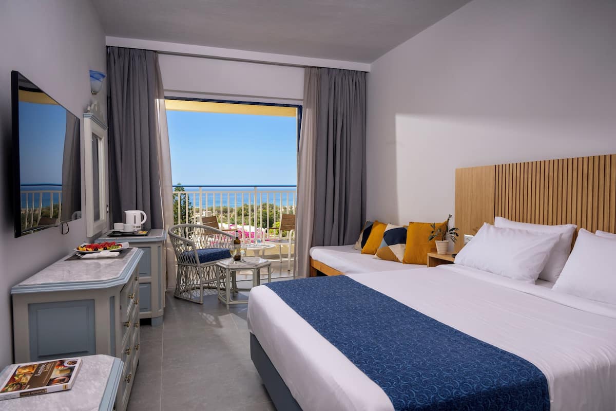 A hotel room with a bed, a desk, a chair, a TV, and a balcony with a view.