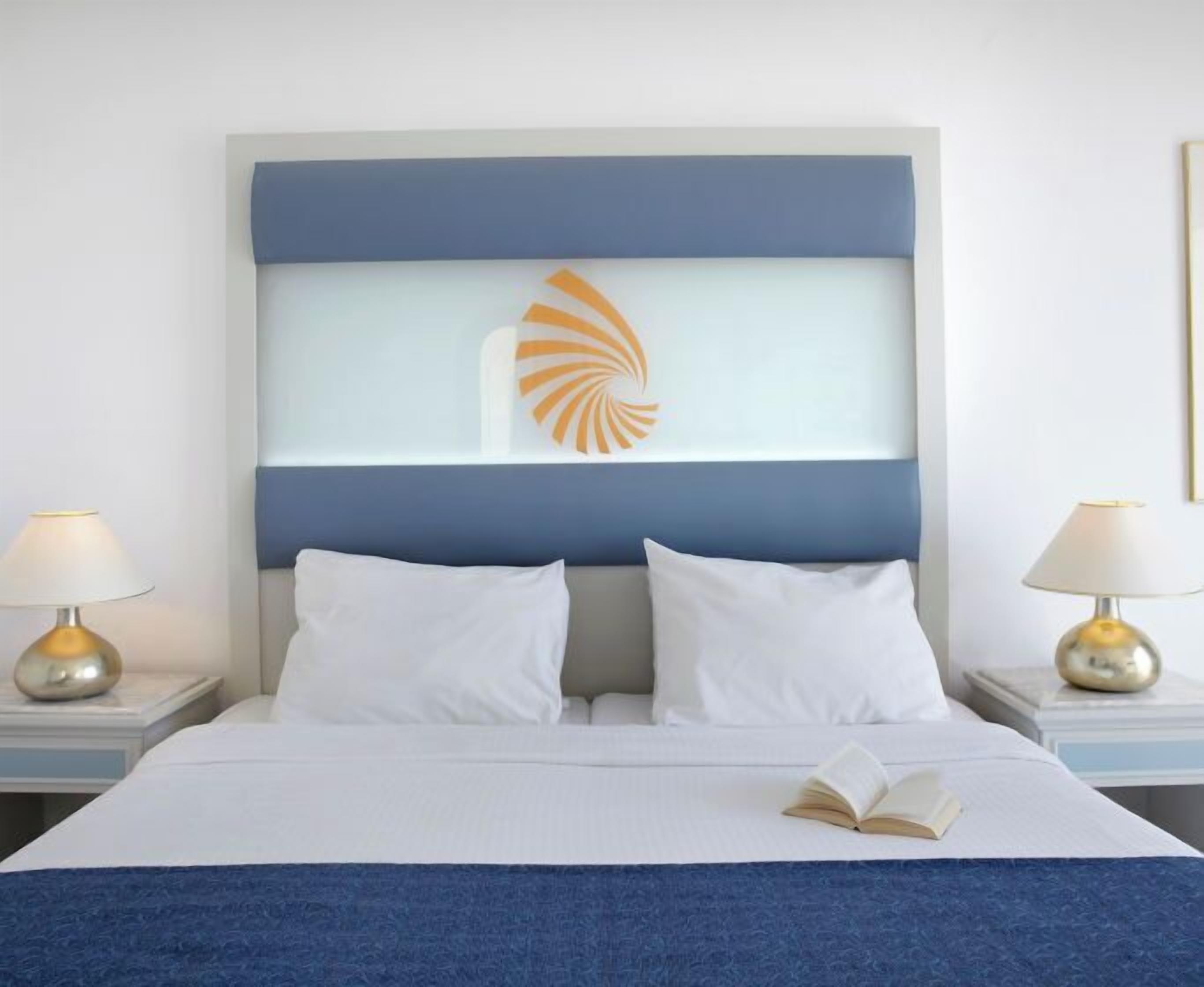 Une chambre d’hôtel avec un lit, deux tables de chevet et une tête de lit décorative.