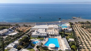 An aerial view of a resort with a large swimming pool, beach access, and a view of the sea. - Mare Blue Hotel (Ierapetra)