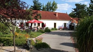 Un bâtiment doté d’un toit recouvert de tuiles rouges, d’une cour pavée et d’un espace extérieur aménagé pour s’asseoir.