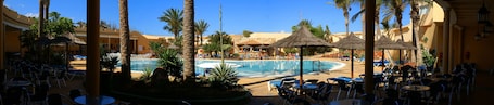 Una piscina techada, una piscina al aire libre, sombrillas