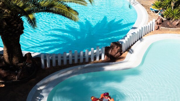 Una piscina de borde curvo rodeada por una valla blanca.