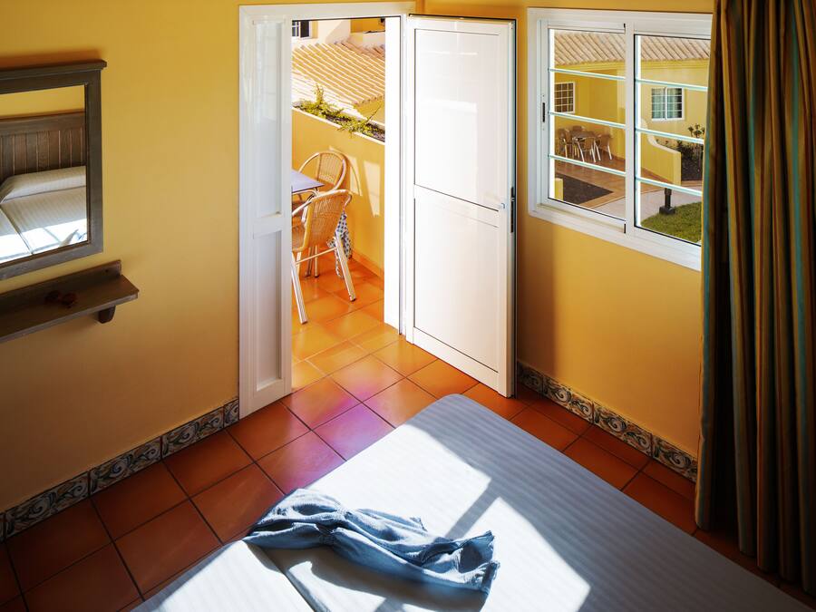 A bedroom with a bed, a window, and a view of an outdoor patio area.