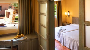Una habitación de hotel con escritorio, cama y ventana con cortinas.