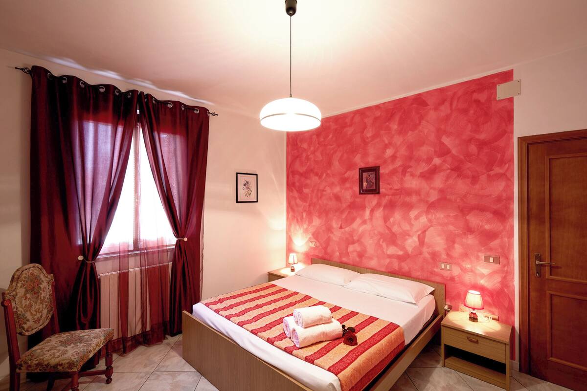 A bedroom with a bed, a chair, a nightstand, and a door.