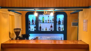 Un espace bar avec des étagères remplies de bouteilles d’alcool et un appareil à café.