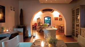 A cozy dining area with a central table, chairs, and a decorative vase. There is a tall, narrow vase on the left and a window with a view of trees in the background. - La Casa di Rodo (Quarrata)