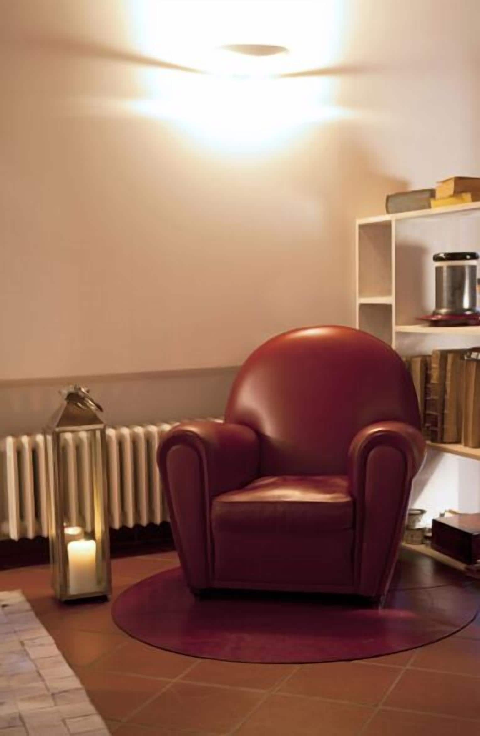Uma sala de estar moderna com uma poltrona de couro vermelha, um radiador branco e uma estante de livros.