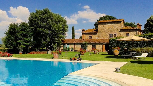 A swimming pool with a clear blue water feature, surrounded by a well-maintained lawn and a stone building with a tiled roof. - La Casa di Rodo (Quarrata)