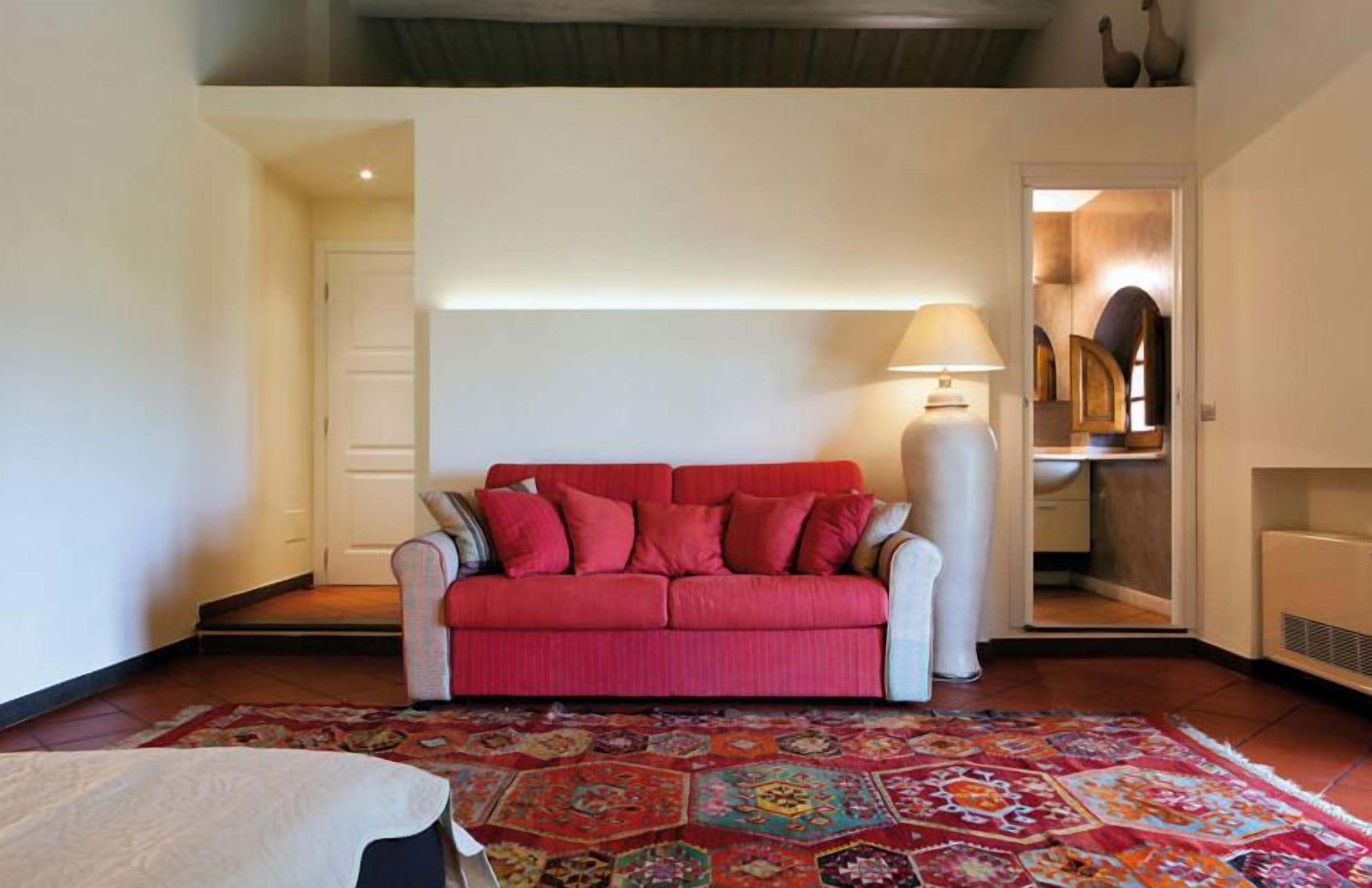 A living room with a red sofa, a patterned rug, and a lamp.