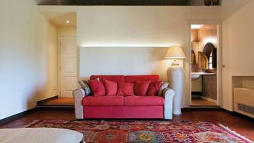 A living room with a red sofa, a patterned rug, and a lamp.