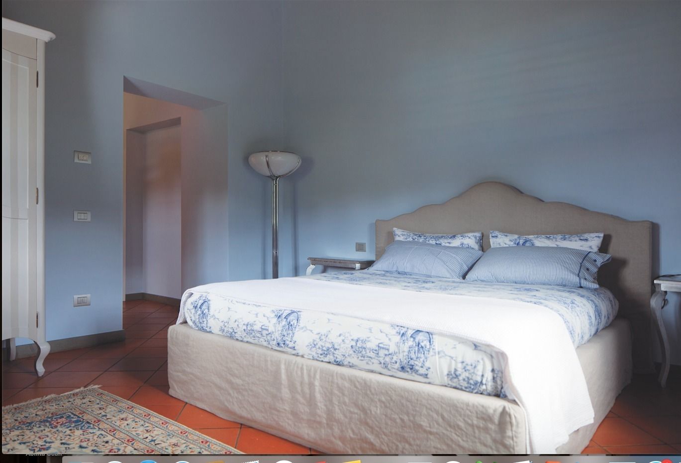 Een slaapkamer met een bed, nachtkastjes, een vloerlamp en een kamerbreed tapijt.
