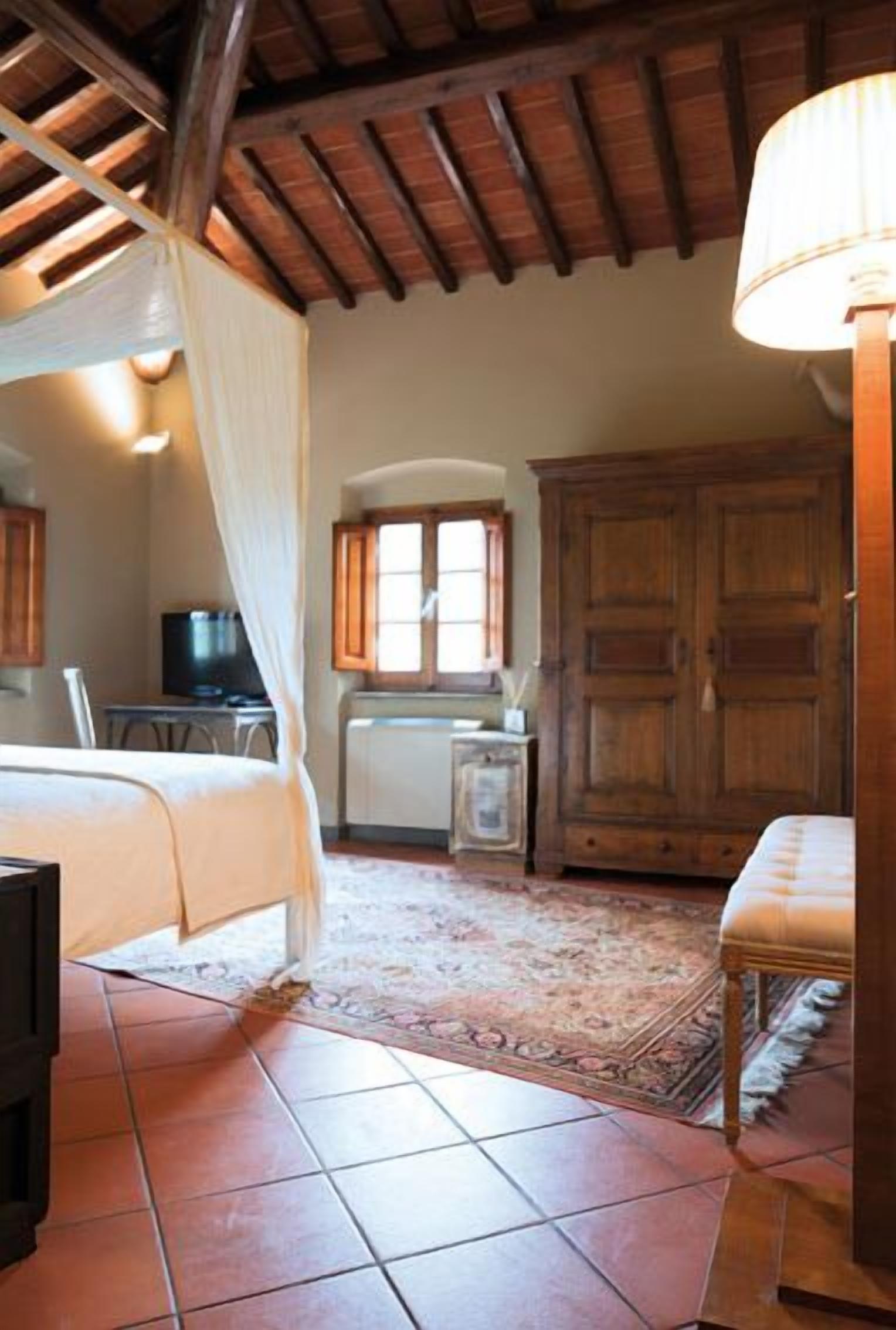 A bedroom with a bed, a desk with a chair, a wardrobe, and a lamp.