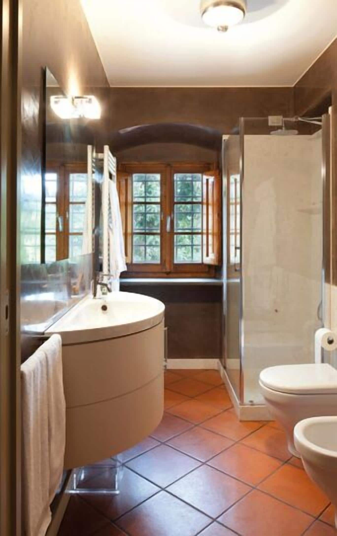 A bathroom with a curved vanity, a toilet, and a glass shower enclosure.