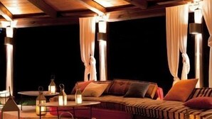 A cozy outdoor seating area with wooden furniture, lanterns, and a patterned rug. - La Casa di Rodo (Quarrata)