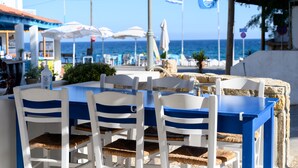 A seaside restaurant with outdoor seating, white and blue chairs, and umbrellas. - Ilioxenia Studio & Apartments (Chios)
